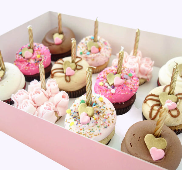Bakers piping frosting onto cupcakes during preparation
