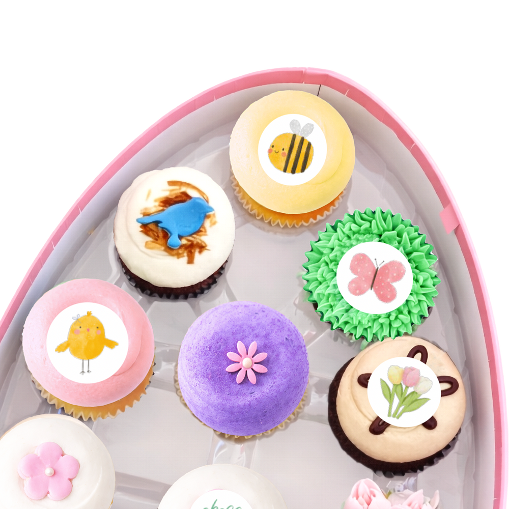 Spring cupcakes with pastel frosting, flowers, bunny and bee designs in gift box