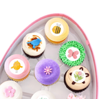 Spring cupcakes with pastel frosting, flowers, bunny and bee designs in gift box
