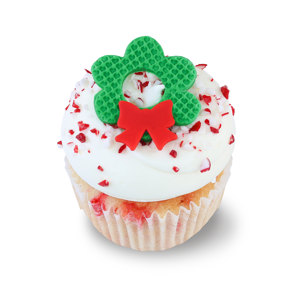 White chocolate peppermint cupcake with candy cane pieces and wreath topper