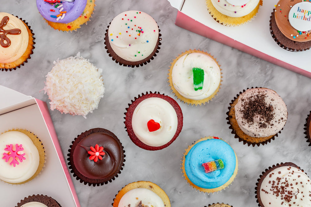 Cupcakes arranged on marble surface with colorful decorations
